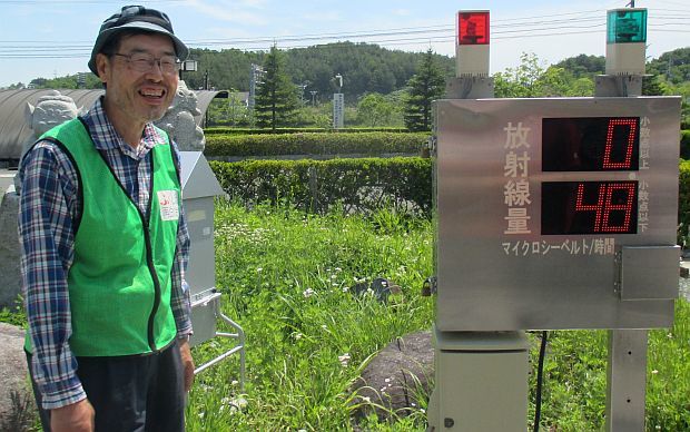 Yoichi Tao the executive director of the volunteer group Ressurect Fukushima stands beside an official radiation meter in Iitate Village Fukushima Prefecture