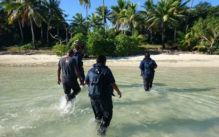 Crew members from Royal New Zealand Navy inshore patrol vessel HMNZS Taupo and personnel from Fiji Revenue and Customs Service wade towards the remote island where over 12 kgs of cocaine were found last week.