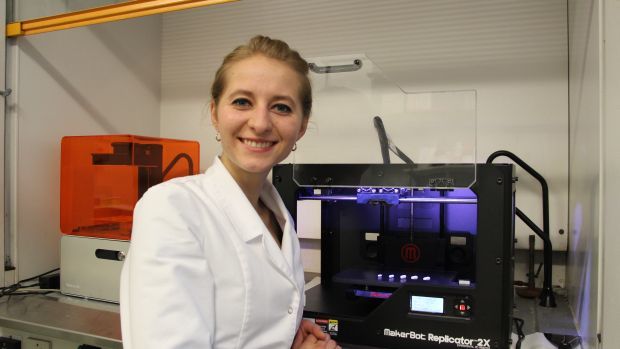 Katarzyna Pietrzak a student in Alhnan research group standing next to different strength theophylline tablets that she made with a D printer