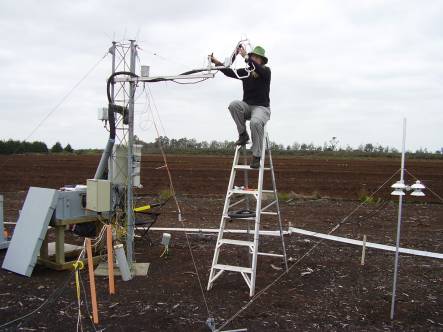 Susanna Rutledge setting up the eddy covariance carbon dioxide measuring system on a tower above bare peat soil 