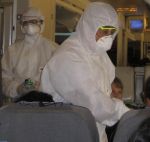 Inspectors on an airplane, checking passengers for symptoms of swine flu